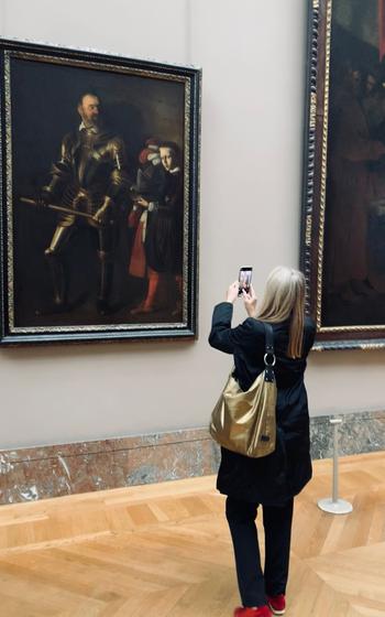 Woman taking a picture of a painting on the wall