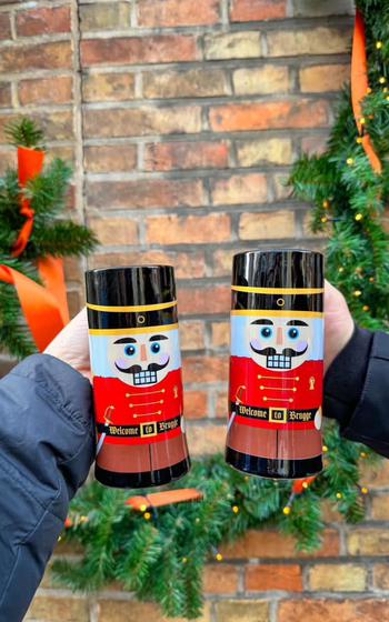 two Nutcrackers painted on two mugs with smiling faces, black hats, and red uniforms. 