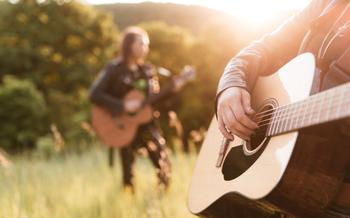 Woman and man playing acoustic guitar at sunset