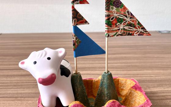 Photo Of toy cow in an egg carton boat with colorful flags