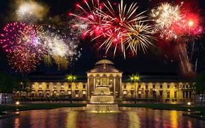 Bright red and gold fireworks light the sky above a lit-up building