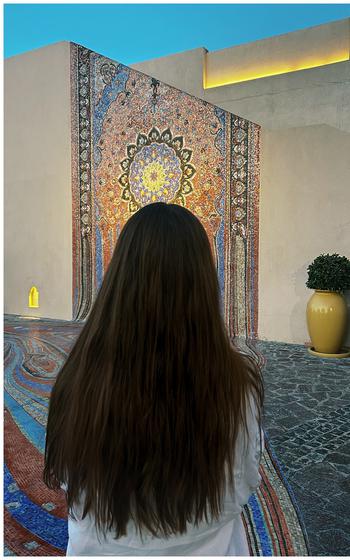 Girl looking at a tapastry adorned on a wall