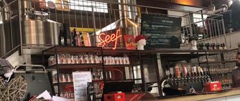 Behind the bar at the brewery is a sign that reads Seef and has shelves of bottled beer