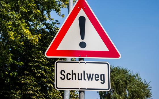 Road sign in german language with warning sign on blue sky background