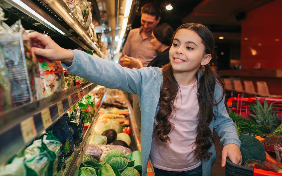 Young parents and daughter in grocery store. 