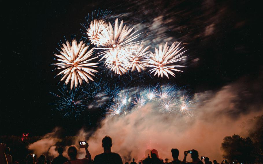 Group of people gathers to watch fireworks ignite in the night’s sky.