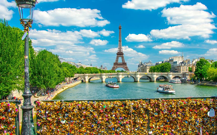 This stunning photo captures the romantic essence of Paris, with a vibrant view of the Eiffel Tower framed by the Seine River. The foreground features a section of the famous “love locks,” where couples leave padlocks as a symbol of their everlasting affection. The charming lamppost, bustling riverboats, and picturesque bridges enhance the scene, embodying the timeless allure of the City of Love. Perfect for travelers and romantics alike, this iconic Parisian setting showcases the city’s unique blend of beauty, history, and romance.