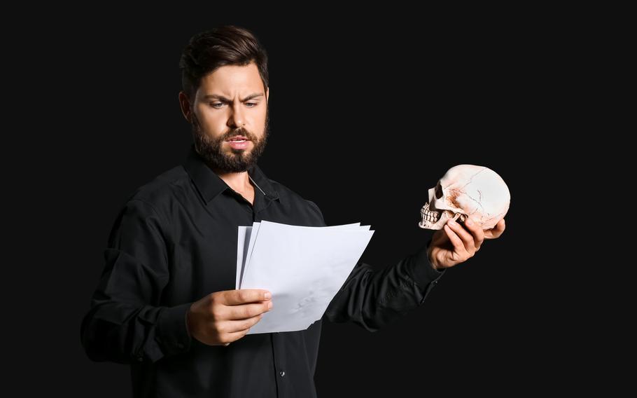 Bearded man holding a skull and documents on a black background