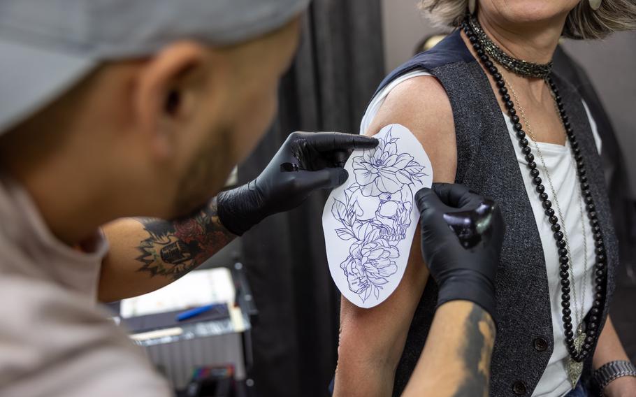 Tattoo artist placing stencil on client’s arm