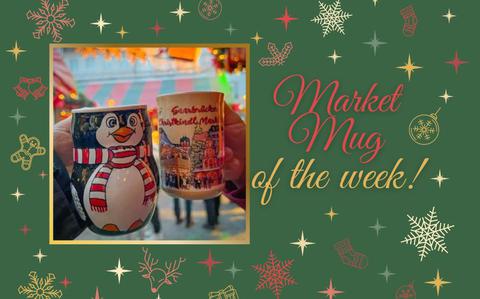 Photo Of Two Christmas market mugs one is in the shape of a penguin with a red and white scarf, the other is a brown mug with a winter village scene wrapping around it. 