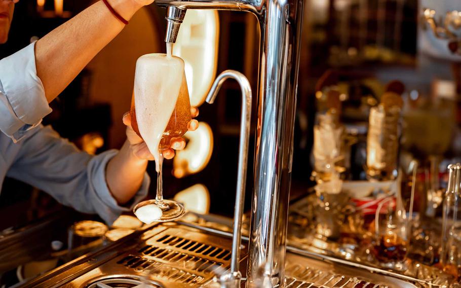 Bartender pouring a glass of Pilsner beer in a tulip-shaped glass