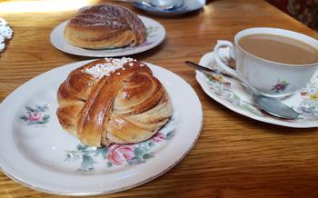 Pastries on white floral-printed plates next to a cup of coffee with spoon