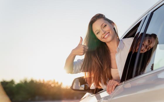 Happy young woman showing thumbs up while in car