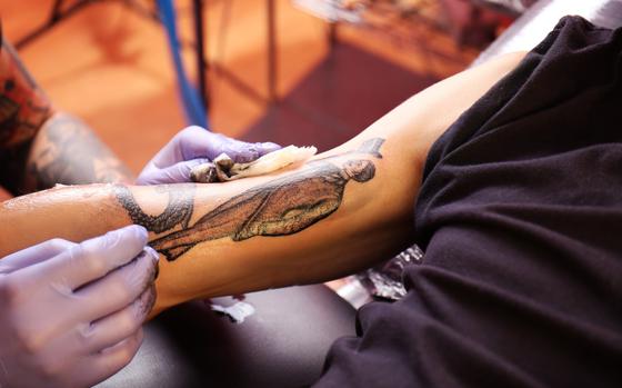 Photo Of Hand of professional artist wiping finished tattoo with hygienic napkin, close up view