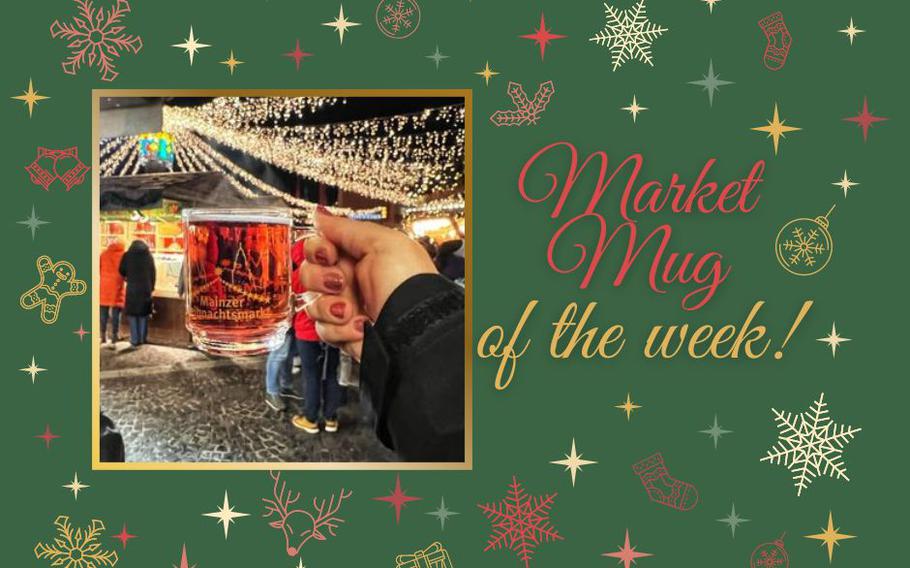 A glass Christmas market mug filled with red glühwein being held against a backdrop of twinkly lights. 