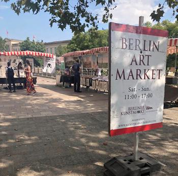 Berlin Art Market sign with outdoor market behind the sign on a sunny day