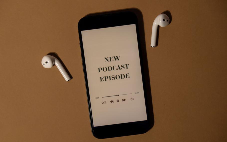 Cellphone reads “New Podcast Episode” with wireless headphones