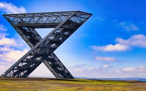 a metal structure stands tall on a hill with a wide-opened sky background