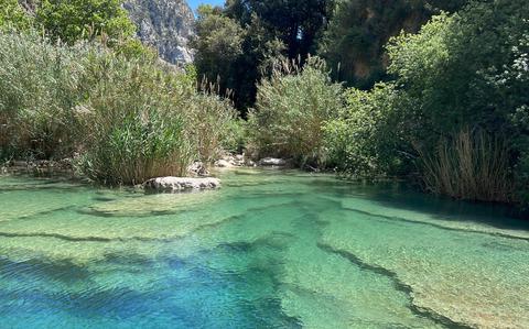 Photo Of Crystal clear water at Cavagrande del Cassibile | one can see the stone/rocky seafloor underneath the water.