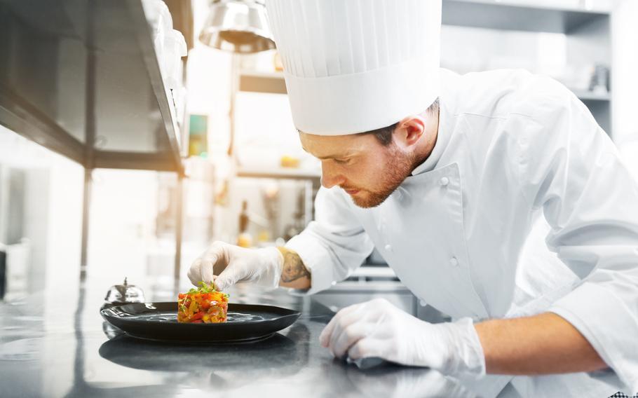 Chef adding final touch to a plated course.