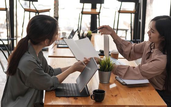 Photo Of Two young businesswomen show joyful expression of success at work smiling happily with a laptop computer in a modern office.