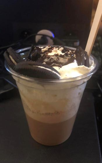 Iced coffee topped with whipped cream, chocolate sauce and oreo cookies