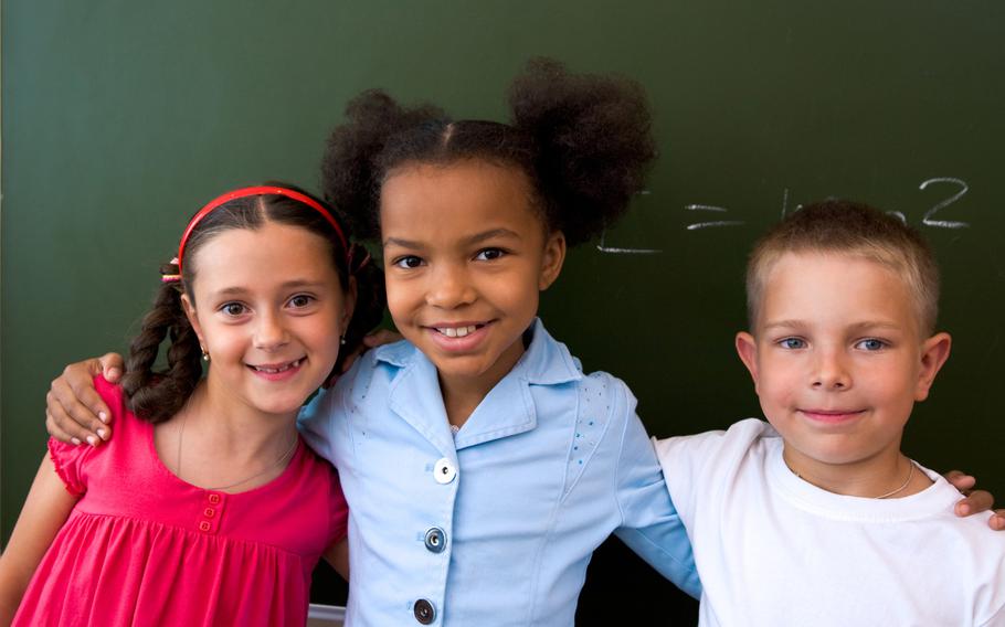Smiling schoolchildren standing in classroom at the elementary school