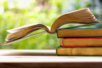 Stack of three books with a fourth book open on top