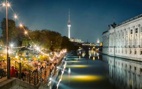 People dancing at summer Strandbar beach party near Spree river at Museum Island with famous TV tower in the background at night, Berlin, Germany