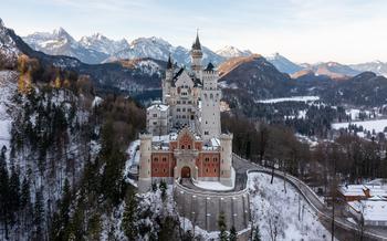 a snowy view of Neuschwanstein castle in the snow with a long road leading up to the castle 