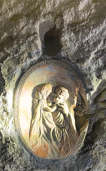 Woman holding a child carving in the stone of the cave