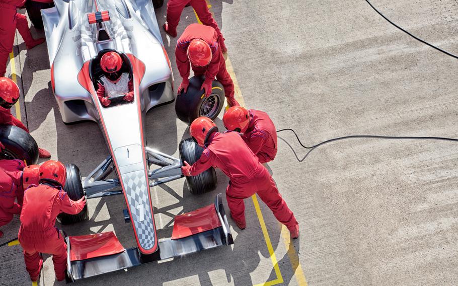 F1 race pit team performing a tire change
