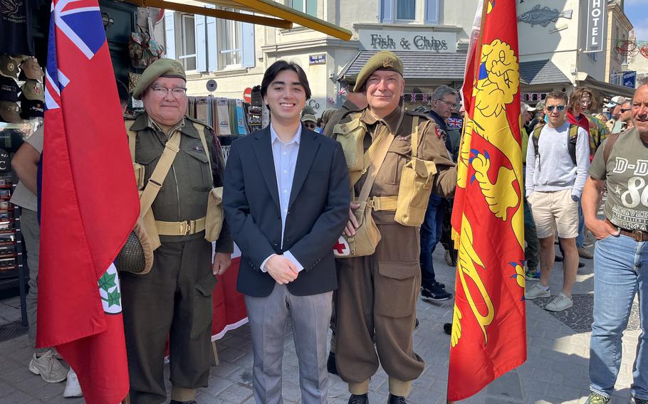 Author standing between two reenactors with each reenactor holding a large red flag outside on a sunny day