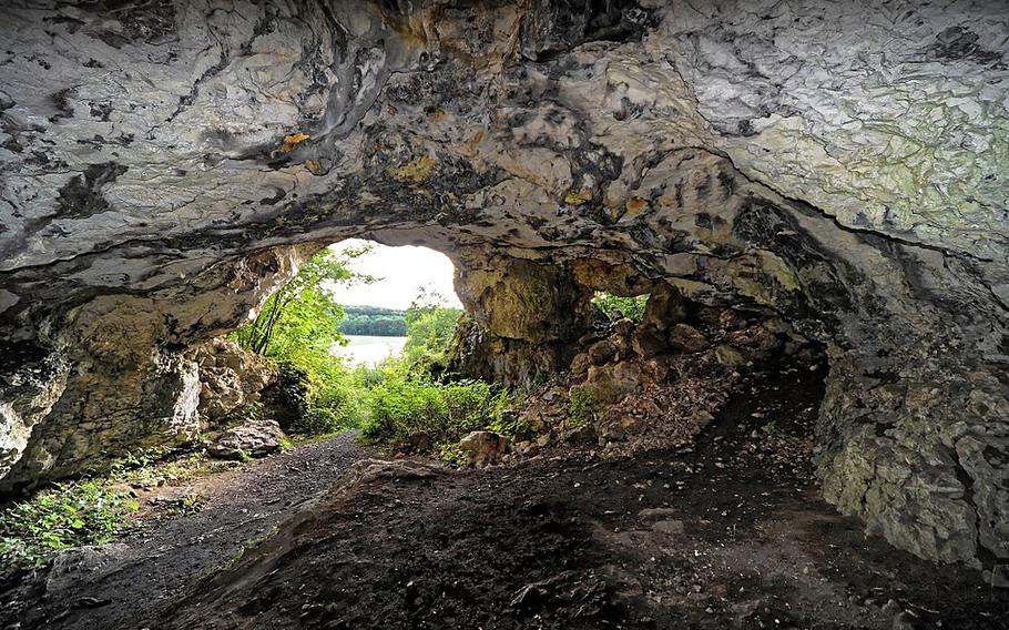 a view of a lake through a cave hole from inside the cave.