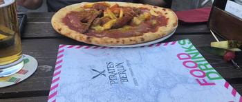 A menu sits in front of a meat-covered personal pizza on a table