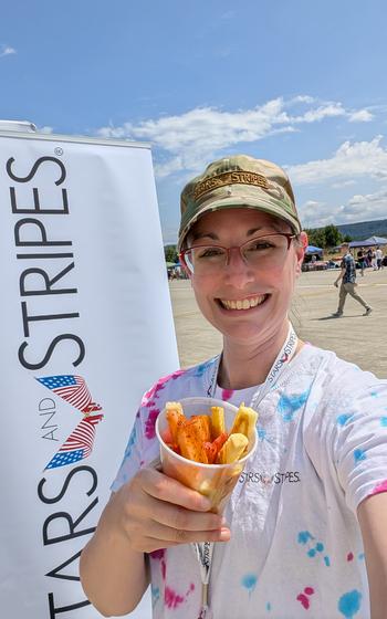 Writer holding seasoned fruit infront of the Stars and Stripes sign