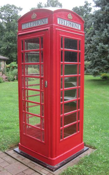 Bright red phonebooth placed on green grass