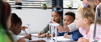 School children sitting around a table and studying wind turbines