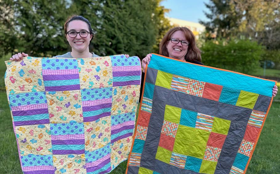 Two Quilt Guild volunteers holding quilts