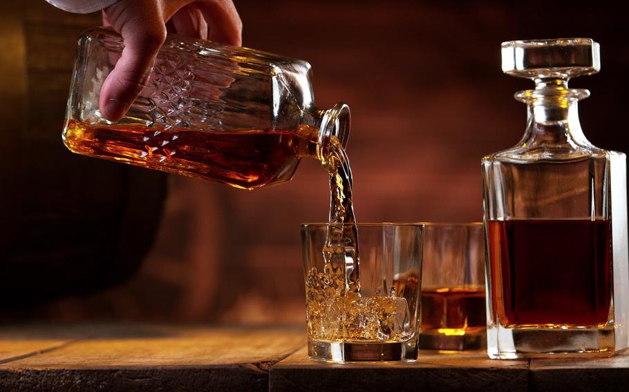 Freeze motion of man hand pouring whisky shot. Vintage interior of village barn.