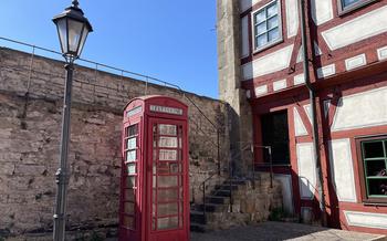 Red British-style phone booth next to a red and white house