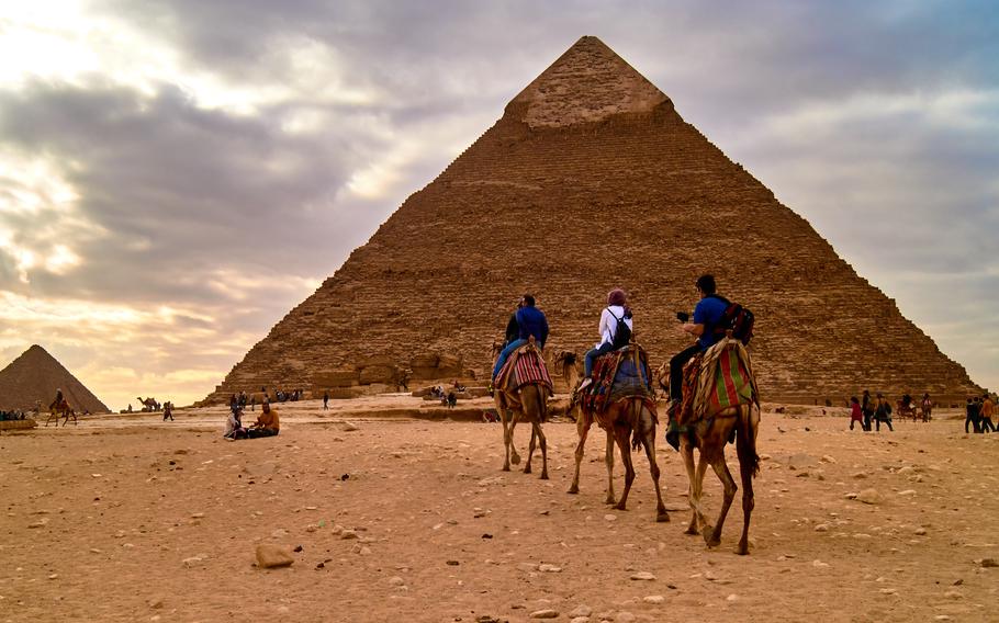 Family riding camels at the pyramids of Giza                           