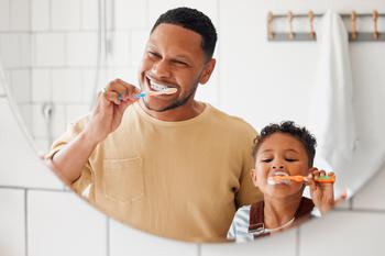 Cheerful father and his child brushing their teeth in the bathroom