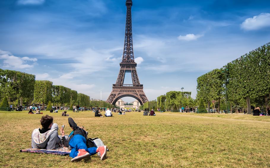 Teenagers lying on the grass of Mars field near the Eiffel tower.