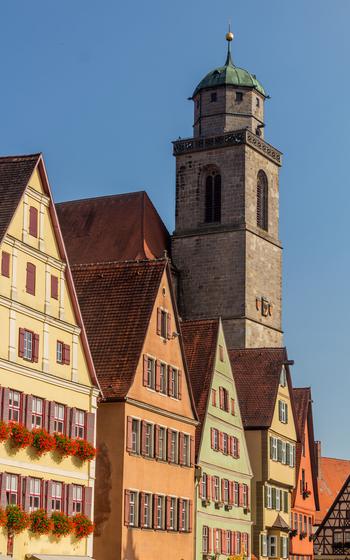 Four yellow, orange and green half-timbered houses line the way to the tower of the Church of Saint George.