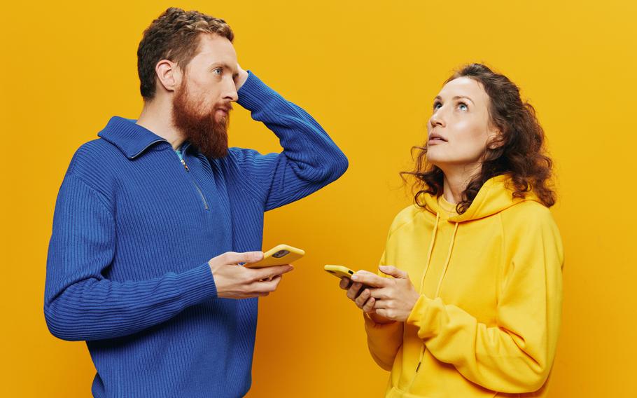 In a vibrant setting, two friends navigate a digital dilemma, their expressions revealing a blend of confusion and curiosity as they engage in a lively discussion about what they see on their phones.