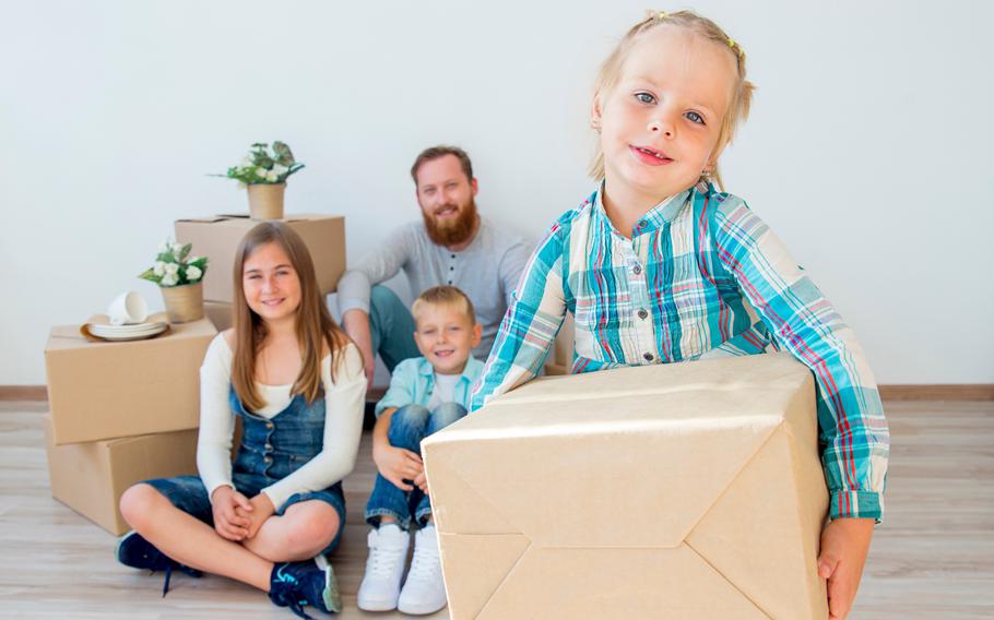 Happy family with boxes moving into a new home and sitting on the floor