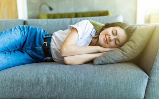 Relaxed young woman lying on sofa in living room at home