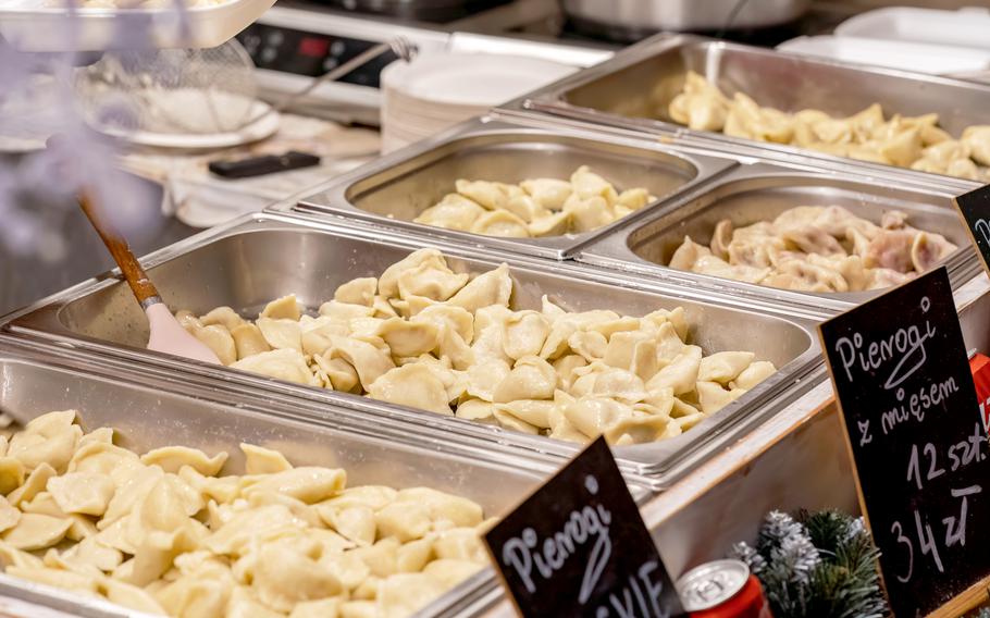Metal containers full of freshly cooked delicious hot steaming Polish pierogi.