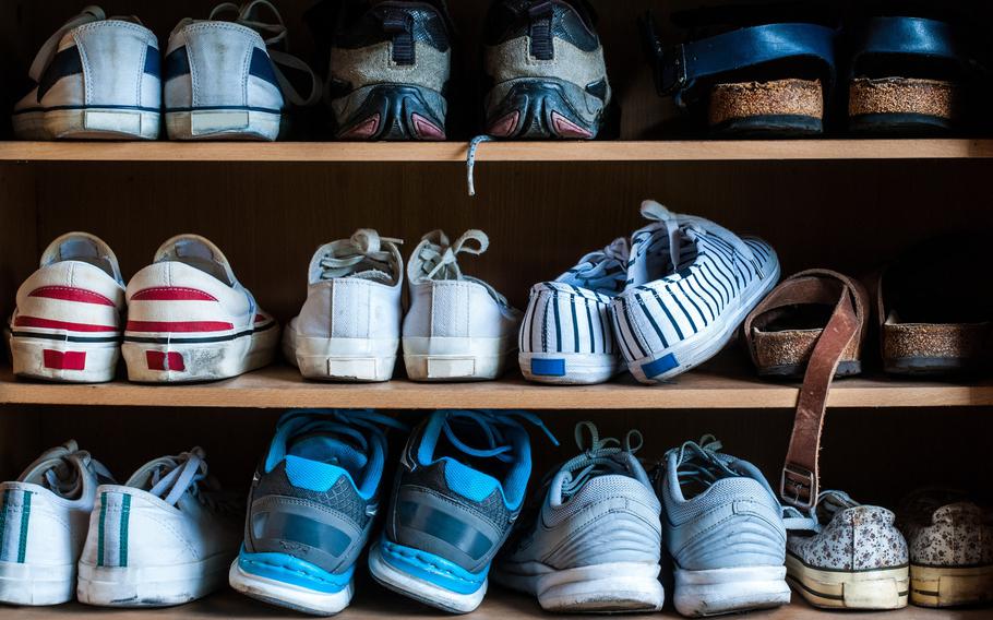 Many old pairs of shoes in a shoe rack.